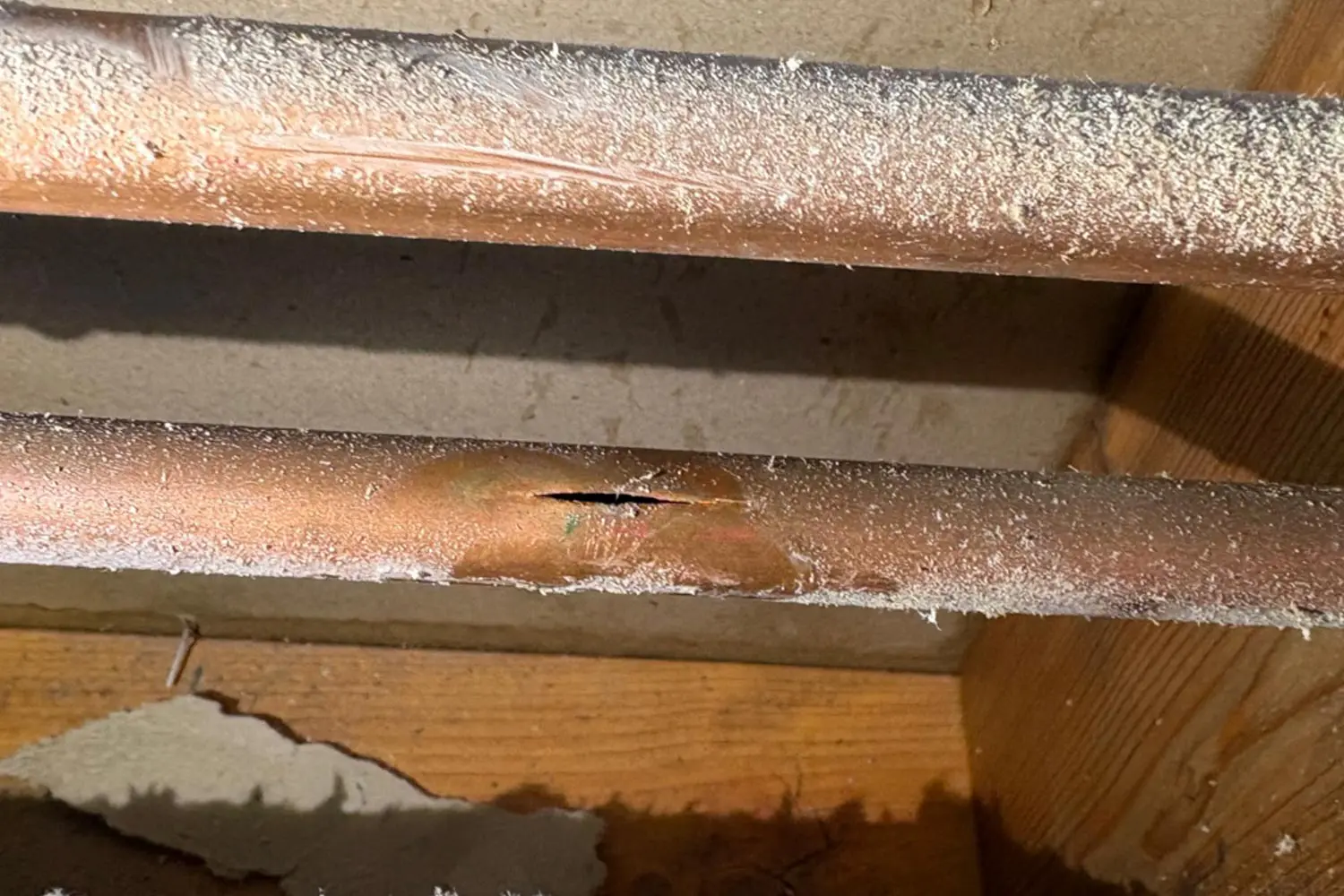 Close-up of a burst copper pipe split open from freezing in a Calgary home.